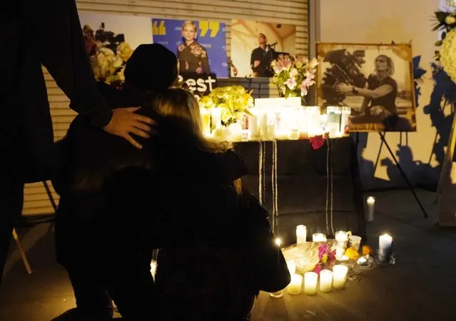 Attendees embrace at a candlelight vigil for the late cinematographer Halyna Hutchins, pictured in photographs in the background, Sunday, October 24, 2021, in Burbank, Calif. A prop firearm discharged last Thursday by actor Alec Baldwin, while producing and starring in a Western movie in Santa Fe, N.M., killed Hutchins and wounded director Joel Souza. (Photo by Chris Pizzello/AP Photo)