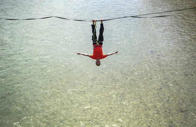 Slakliner Lukas Irmler hangs at a slack line as he performs over the river Isar in Munich on Tuesday, April 16, 2019. (Photo by Sina Schuldt/dpa via AP Photo)