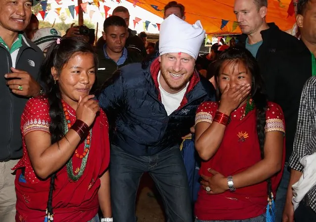Prince Harry is dragged to dance by two young girls as torrential rain begins during a visit to the village of Leorani in the Himalayan foothills on day three of his visit to Nepal on March 21, 2016 in Bardia, Nepal. Prince Harry is on a five day visit to Nepal, his first official tour of the country. (Photo by Chris Jackson/Getty Images)