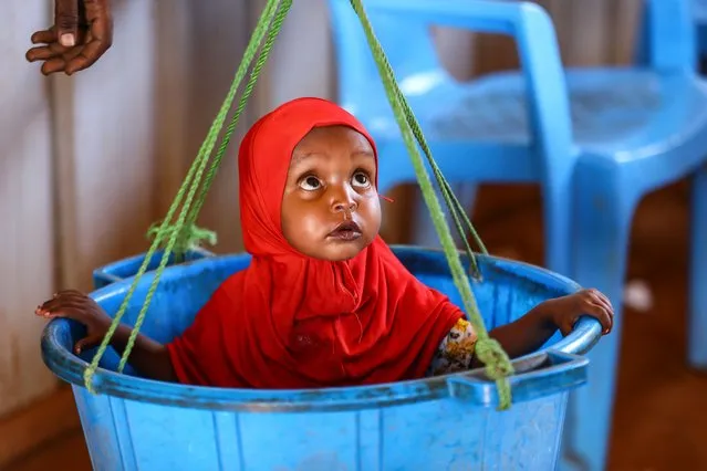 A baby of an internally displaced woman gets weighed during a doctor and nutritionist review to prevent malnutrition at a makeshift clinic in Ladan IDP camp, on the outskirts of Dollow, in Jubaland state, Somalia, 30 January 2024. (Photo by Daniel Irungu/EPA/EFE)