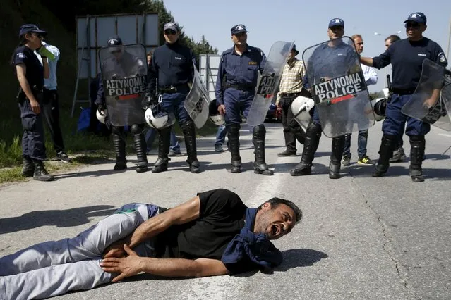 A man lies in pain, after his foot was stepped on, in front of Greek policemen as migrants and refugees block the highway near the Greek-Macedonian border near the village of Evzoni, Greece, April 4, 2016. (Photo by Marko Djurica/Reuters)
