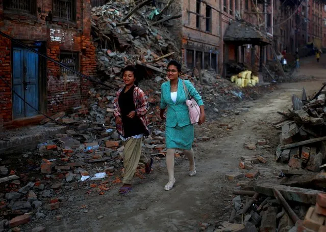 Women walk through debris in the early morning hours in Bhaktapur near Kathmandu, Nepal, May 14, 2015. The Himalayan nation is still reeling from a devastating quake measuring 7.8 last month that killed more than 8,000 people and injured close to 20,000. (Photo by Ahmad Masood/Reuters)