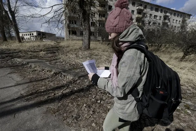 A woman looks at a map as she visits the ghost town of a former Soviet military radar station near Skrunda, Latvia, April 9, 2016. (Photo by Ints Kalnins/Reuters)