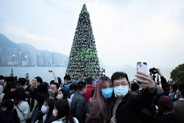 A couple poses for a photo in front of a giant Christmas tree during Christmas at the West Kowloon cultural district in Hong Kong on December 25, 2021. (Photo by Bertha Wang/AFP Photo)