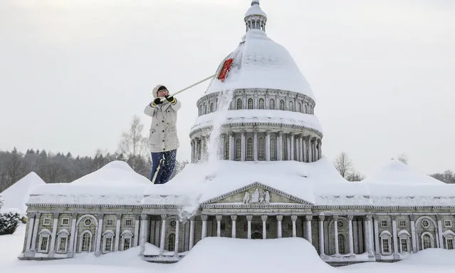 A staff member clears snow from the Washington D.C. Capitol in Miniworld, Lichtenstein, Germany on February 9, 2021. There are over 100 world-famous monuments on a scale of 1:25 in the amusement park. Almost 2 million people have already visited the mini world. (Photo by Jan Woitas/dpa-Zentralbild/dpa)