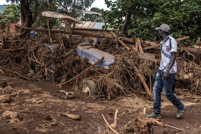 A man walks next to a damaged tractor carried by waters in an area heavily affected by torrential rains and flash floods in the village of Kamuchiri, near Mai Mahiu, on April 29, 2024. At least 45 people died when a dam burst its banks near a town in Kenya's Rift Valley, police said on April 29, 2024, as torrential rains and floods battered the country. The disaster raises the total death toll over the March-May wet season in Kenya to more than 120 as heavier than usual rainfall pounds East Africa, compounded by the El Nino weather pattern. (Photo by Luis Tato/AFP Photo)