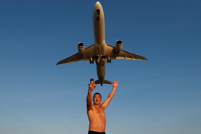 Ivan, a tourist from Russia, takes a selfie at Mai Khao Beach as a plane takes off from Phuket International Airport in Phuket, Thailand, January 17, 2022. (Photo by Jorge Silva/Reuters)
