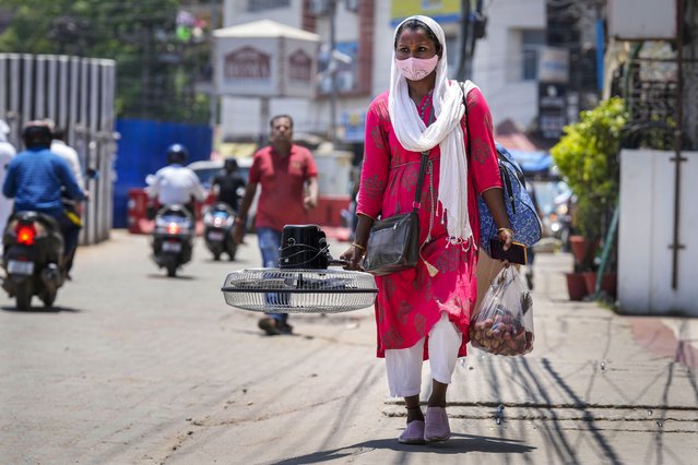 A woman carries a fan purchased from a market on a hot summer day in Guwahati, India, Saturday, May 25, 2024. (Photo by Anupam Nath/AP Photo)