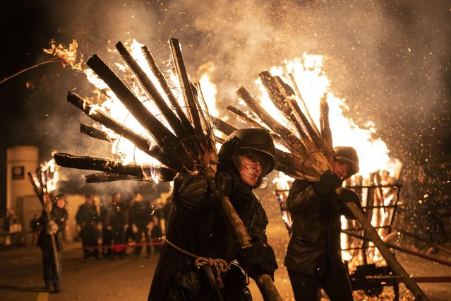 Participants carry burning torches during the “Chienbaese” procession in Liestal near Basel, Switzerland, 26 Feburary 2023. The parade continues through the dark lanes of the old town, bringing the light and the hope of warmer days to the residents. 9Photo by Ennio Leanza/EPA)