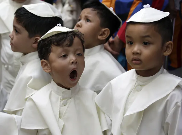 A boy dressed as a Pope, yawns as he prepares to join a parade in celebration of the canonization or the elevation to sainthood in the Vatican of Roman Catholic Pope John Paul II and Pope John XXIII Sunday, April 27, 2014, at suburban Quezon city, northeast of Manila, Philippines. Pope Francis declared his two predecessors John XXIII and John Paul II saints on Sunday before hundreds of thousands of people in St. Peter's Square, an unprecedented ceremony made even more historic by the presence of retired Pope Benedict XVI. (Photo by Bullit Marquez/AP Photo)