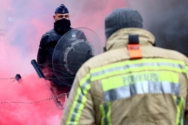 A police officer guards the area as firefighters attend a protest in Brussels, Belgium on March 7, 2023. (Photo by Yves Herman/Reuters)