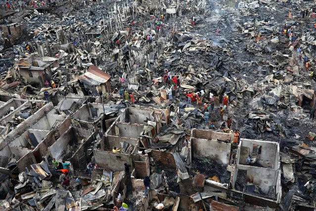 Slum dwellers are seen searching for their belongings from ashes after fire broke out on their shelters in Dhaka, Bangladesh, August 17, 2019. (Photo by Mohammad Ponir Hossain/Reuters)