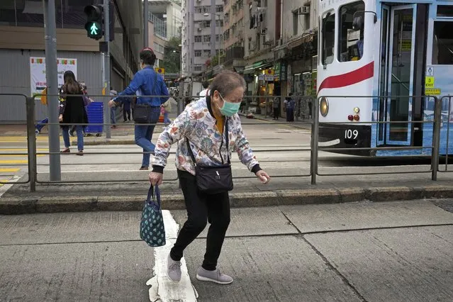 An elderly woman wearing a face mask walks alone a street in Hong Kong, Sunday, March 13, 2022. (Photo by Kin Cheung/AP Photo)