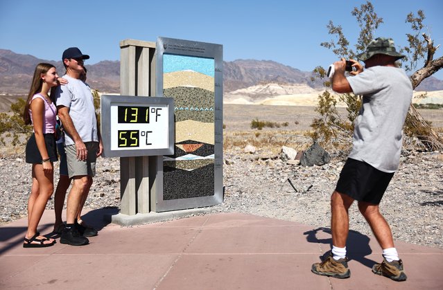 Tourists pose next to an unofficial thermometer in the afternoon heat at Furnace Creek Visitor Center, during a long-duration heat wave which is impacting much of California, on July 9, 2024 in Death Valley National Park, California. Park visitors have been warned, “Travel prepared to survive” as temperatures are predicted to reach close to record highs this week. Death Valley is the hottest and driest place in the United States. (Photo by Mario Tama/Getty Images)