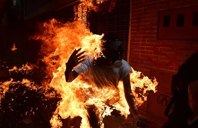 A demonstrator catches fire during clashes with riot police within a protest against Venezuelan President Nicolas Maduro, in Caracas on May 3, 2017. Venezuela' s angry opposition rallied Wednesday vowing huge street protests against President Nicolas Maduro' s plan to rewrite the constitution and accusing him of dodging elections to cling to power despite deadly unrest. (Photo by Ronaldo Schemidt/AFP Photo)