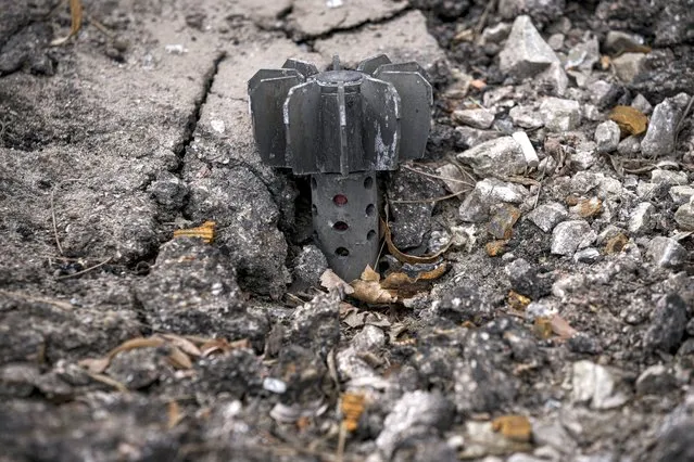A part of a mortar shell sticks out of the asphalt in Stoyanka, Ukraine, Sunday, March 27, 2022. (Photo by Vadim Ghirda/AP Photo)