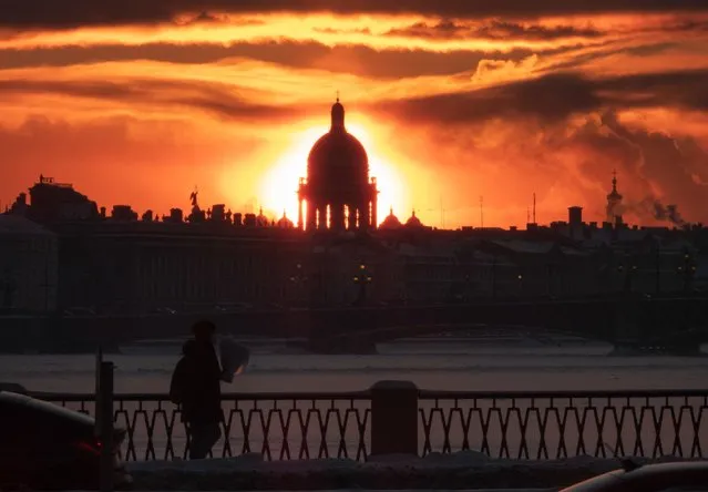 One of the city's landmarks St. Isaac's Cathedral is silhouetted as the sun sets in St. Petersburg, Russia, Tuesday, January 11, 2022. (Photo by Dmitri Lovetsky/AP Photo)