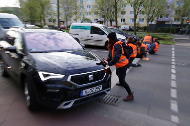 A climate activist from Last Generation (“Letzte Generation”) attempts to stop a car from driving past moments after she and colleagues sat down to block the intersection on Landsberger Allee on April 27, 2023 in Berlin, Germany. Last Generation is continuing its week of disruptive protests across Berlin today in order to campaign for a nationwide speed limit and other climate friendly measures. (Photo by Sean Gallup/Getty Images)