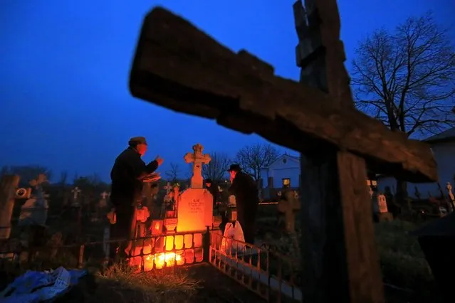 A couple light a small fire on their family grave during Orthodox Maundy Thursday memorial for the departed ones, at a cemetery in Copaciu, Romania, 21 April 2022. Orthodox believers in the village traditionally gather in the early morning hours to light fires and spread fresh water on the graves, and share food in the memory of their departed relatives. Orthodox believers will celebrate Easter on 24 April 2022. (Photo by Robert Ghement/EPA/EFE)
