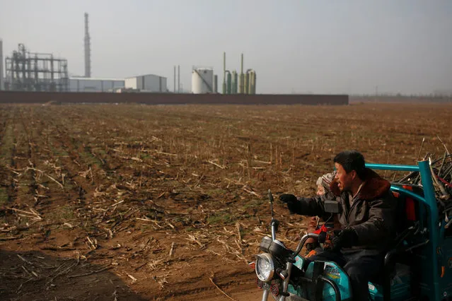 A villager and a boy ride on an electric tricylce past the Guantao Chemical Industry Park outside the village of East Luzhuang, Hebei province, February 23, 2017. (Photo by Thomas Peter/Reuters)