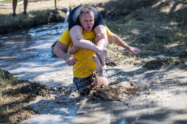 Participants compete in a wife-carrying championship in Tapiobicske, Hungary on August 10, 2024. (Photo by Marton Monus/Reuters)