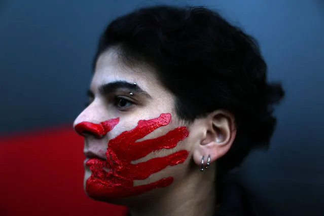 A Lebanese woman poses with her face painted with a red hand during a demonstration against sexual harassment, rape and domestic violence in the Lebanese capital Beirut on December 7, 2019. (Photo by Patrick Baz/Abaad/AFP Photo)