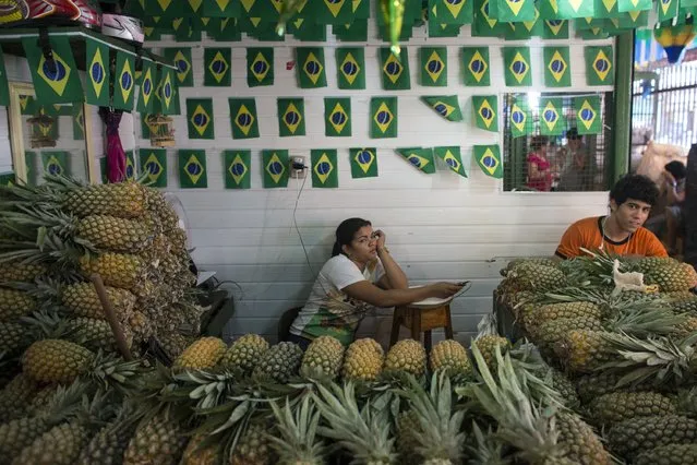 A market trader, adjacent to the port in Manaus, relaxes under decorations bearing the Brazilian national flag on June 14, 2014 in Manaus, Brazil. Group D teams, England and Italy, will play their opening match of the 2014 FIFA World Cup when they meet in Manaus this evening. (Photo by Oli Scarff/Getty Images)