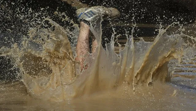 A participant dives into the mud pool during the Mud Day athletic event at El Goloso Military base on the outskirts of Madrid, Spain, Saturday, June 11, 2016. (Photo by Paul White/AP Photo)