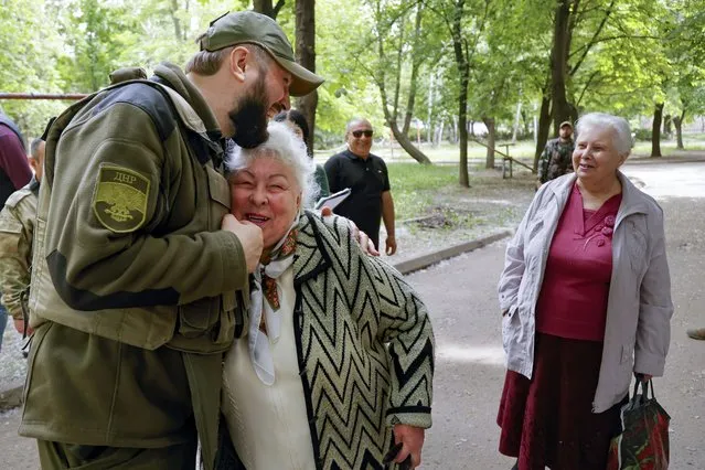 A serviceman of Donetsk People's Republic militia embraces a local woman in Svitlodarsk, in territory under the government of the Donetsk People's Republic, eastern Ukraine, Thursday, May 26, 2022. Svetlodarsk came under the control of the forces of the people's republics, as a result of the offensive of their units and with the support of Russian troops. (Photo by Alexei Alexandrov/AP Photo)