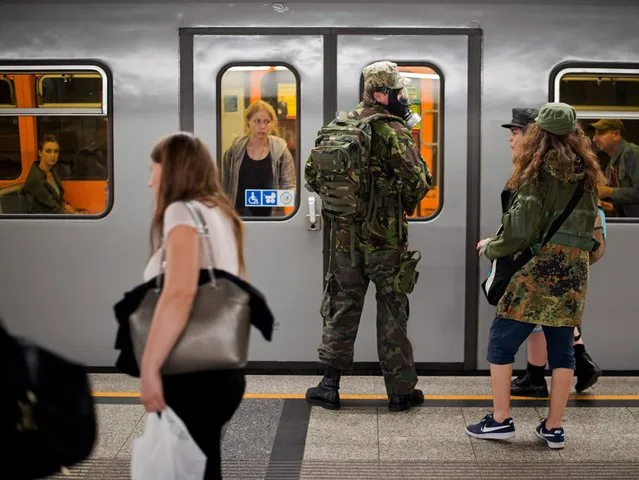 A military styled man (C) wearing a gas mask waits prior entering a subway train at the Volkstheater subway station in Vienna, Austria, 14 June 2016. (Photo by Christian Bruna/EPA)
