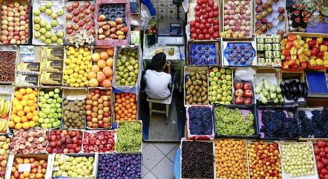 A boy takes a meal break at a fruit stall in the central market in Kazan, Russia, August 11, 2015. (Photo by Hannibal Hanschke/Reuters)