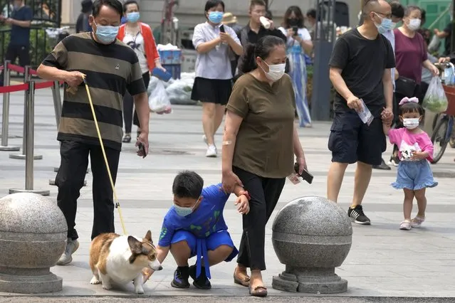 Residents wear masks as they go about their day, Thursday, June 16, 2022, in Beijing. Authorities are trying to contain a new outbreak of COVID linked to a nightclub with mass COVID test and closure of restaurants and entertainment centers in the Chinese capital. (Photo by Ng Han Guan/AP Photo)