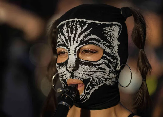 A woman with a mask plays a flute during a march marking the International Day for the Elimination of Violence against Women, in Santiago, Chile, Thursday, November 25, 2021. (Photo by Esteban Felix/AP Photo)