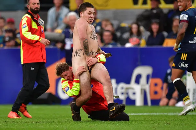 A streaker races across the field and is caught by security during the Super Rugby match between New Zealand's Highlanders and South Africa's Sharks at Forsyth Barr Stadium in Dunedin on February 7, 2020. (Photo by Marty Melville/AFP Photo)