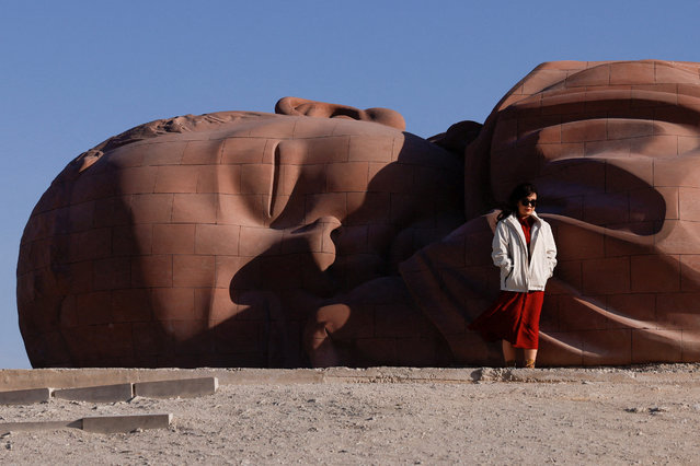 A tourist poses for pictures in front of a sculpture at Gobi desert in Guazhou, during an organised media tour in Gansu province, China on October 17, 2024. (Photo by Tingshu Wang/Reuters)