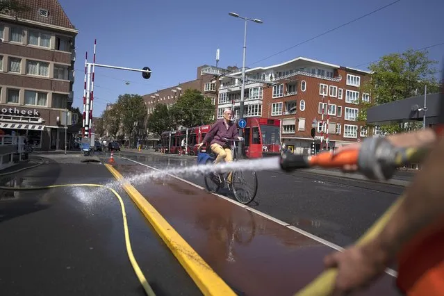 As the Dutch capital baked in the heat, municipal workers sprayed water on bridges over the city's canals to prevent metal in the constructions expanding which can jam them shut blocking boat traffic, in Amsterdam, Tuesday, July 19, 2022. (Photo by Peter Dejong/AP Photo)