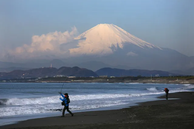 Backdropped by snow-capped Mount Fuji, a man casts his fishing rod into the ocean on a quiet beach in Fujisawa, Japan, Thursday, February 27, 2020. According to local businesses in the area, the number of visitors has dropped significantly since the outbreak of COVID-19. (Photo by Jae C. Hong/AP Photo)