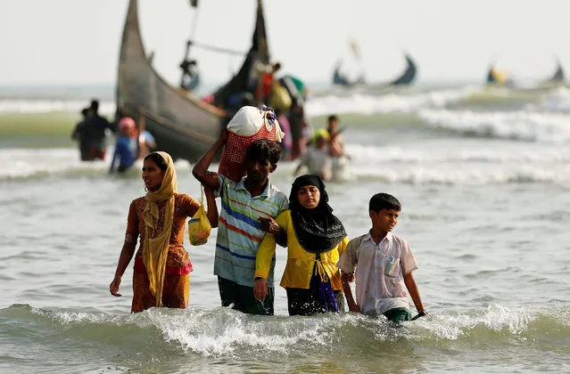Rohingya refugees walk to the shore with his belongings after crossing the Bangladesh-Myanmar border by boat through the Bay of Bengal in Teknaf, Bangladesh, September 5, 2017. (Photo by Mohammad Ponir Hossain/Reuters)