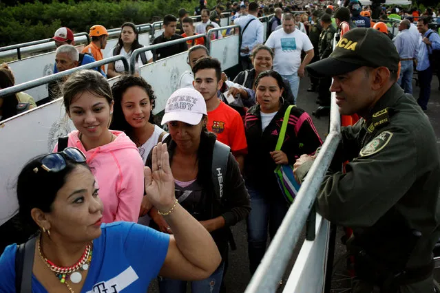 A Colombian police officer looks on as people line up to cross over the Simon Bolivar international bridge to Colombia to take advantage of the temporary border opening in San Antonio del Tachira, Venezuela, July 17, 2016. (Photo by Carlos Eduardo Ramirez/Reuters)