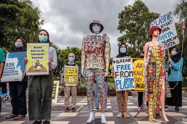 Environmental activists display placards next to mannequins dressed with plastic waste during a campaign against climate change to mark 'Earth Day' in Surabaya on April 22, 2022. (Photo by Juni Kriswanto/AFP Photo)