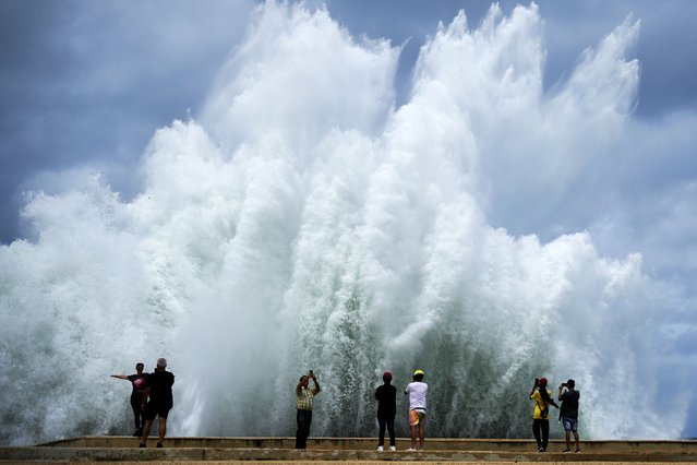 People take photos of the spray from waves crashing against the Malecon seawall, brought by the passing of Hurricane Milton in the Gulf of Mexico, in Havana, Cuba, Wednesday, October 9, 2024. (Photo by Ramon Espinosa/AP Photo)