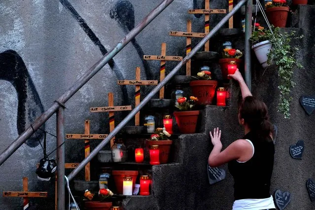 People light candles as the gather in front of the Love Parade Memorial located at the site of the accident that left 21 people dead on 24 July 2010, in Duisburg, Germany, 24 July 2016. (Photo by Patrik Stollarz/AFP Photo)