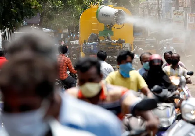People wearing face maks ride motorcycles as a municipal vehicle decontaminates a road during a 21-day nationwide lockdown to slow the spreading of coronavirus disease (COVID-19), in Chennai, India, April 9, 2020. (Photo by P. Ravikumar/Reuters)