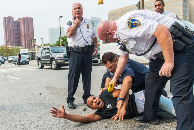 A protester is restrained after fighting with police as protests moved into the street on the first day of pretrial motions for six police officers charged in connection with the death of Freddie Gray in Baltimore, Maryland September 2, 2015. Baltimore City Circuit Court Judge Barry Williams on Wednesday rejected defense motions to drop charges against six police officers in the case of a black man who died in April from injuries in police custody. (Photo by Bryan Woolston/Reuters)