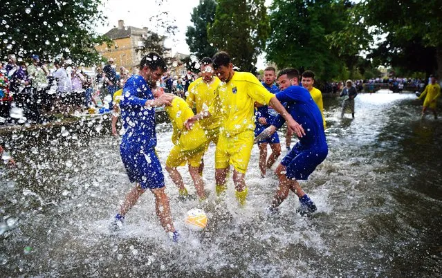 Footballers from Bourton Rovers create a splash as they fight for the ball during the annual traditional River Windrush football match, which has been taking place for over 100 years, in the Cotswolds village of Bourton-in-the-Water, Gloucestershire on Monday, August 29, 2022. (Photo by Ben Birchall/PA Images via Getty Images)
