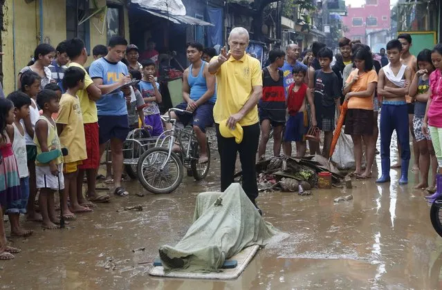 A priest blesses the body of a victim who drowned in floodwaters a day after tropical storm Fung-Wong inundated the Philippine capital Manila September 20, 2014. Heavy rain in the Philippine capital, Manila, caused flooding in many areas on Friday, shutting schools, government offices and financial markets as a tropical storm made landfall to the north. (Photo by Erik De Castro/Reuters)