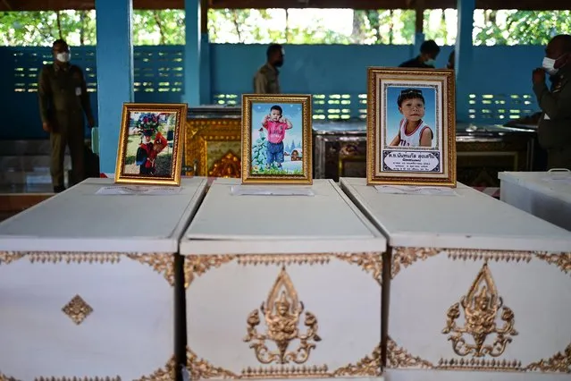 Portraits of young victims of a mass shooting in a nursery are displayed atop their coffins as funeral preparations get underway at Wat Si Uthai temple in Thailand's northeastern Nong Bua Lam Phu province on October 7, 2022. Weeping, grief-stricken families gathered on October 7 outside a Thai nursery where an ex-policeman murdered two dozen children in one of the kingdom's worst mass killings. (Photo by Manan Vatsyayana/AFP Photo)