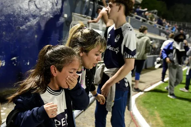 Fans of Gimnasia de La Plata react to tear gas on the field during a local tournament match between Gimnasia de La Plata and Boca Juniors in La Plata, Argentina, Thursday, October 6, 2022. The match was suspended after tear gas thrown by the police outside the stadium wafted inside affecting the players as well as fans who fled to the field to avoid its effects. (Photo by Gustavo Garello/AP Photo)