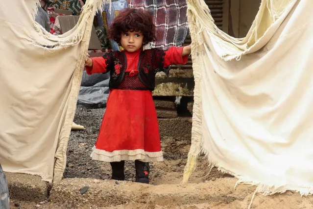 A girl stands at the entrance of her family's hut following a rainy day at a camp for internally displaced people in Marib, Yemen on August 7, 2022. (Photo by Ali Owidha/Reuters)