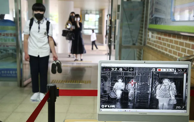 A student wearing a face mask to help protect against the spread of the new coronavirus stands to have his body temperatures checked before entering his classroom at a middle school in Jeonju, South Korea, Wednesday, Jun 3, 2020. (Photo by Na Bo-bae/Yonhap via AP Photo)